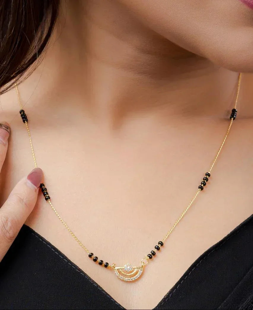 Gold necklace with black beads worn by a person