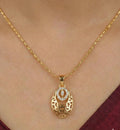 Gold necklace with a pendant on a person wearing a burgundy top.