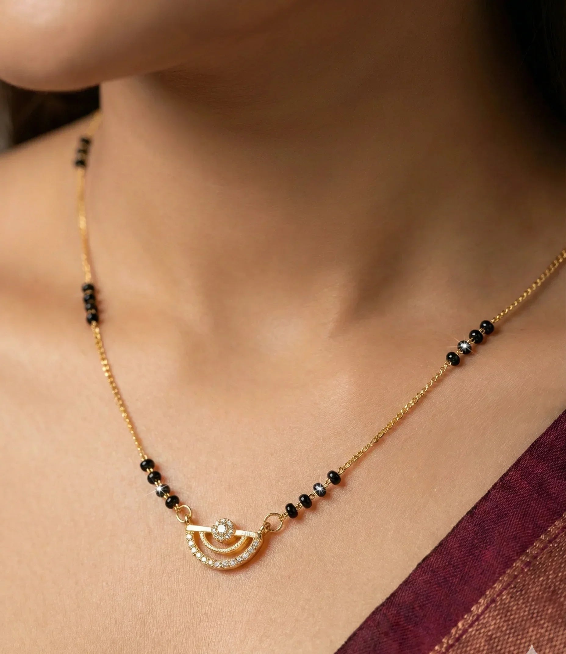 Necklace with black beads and gold accents worn by a person, with a blurred background.
