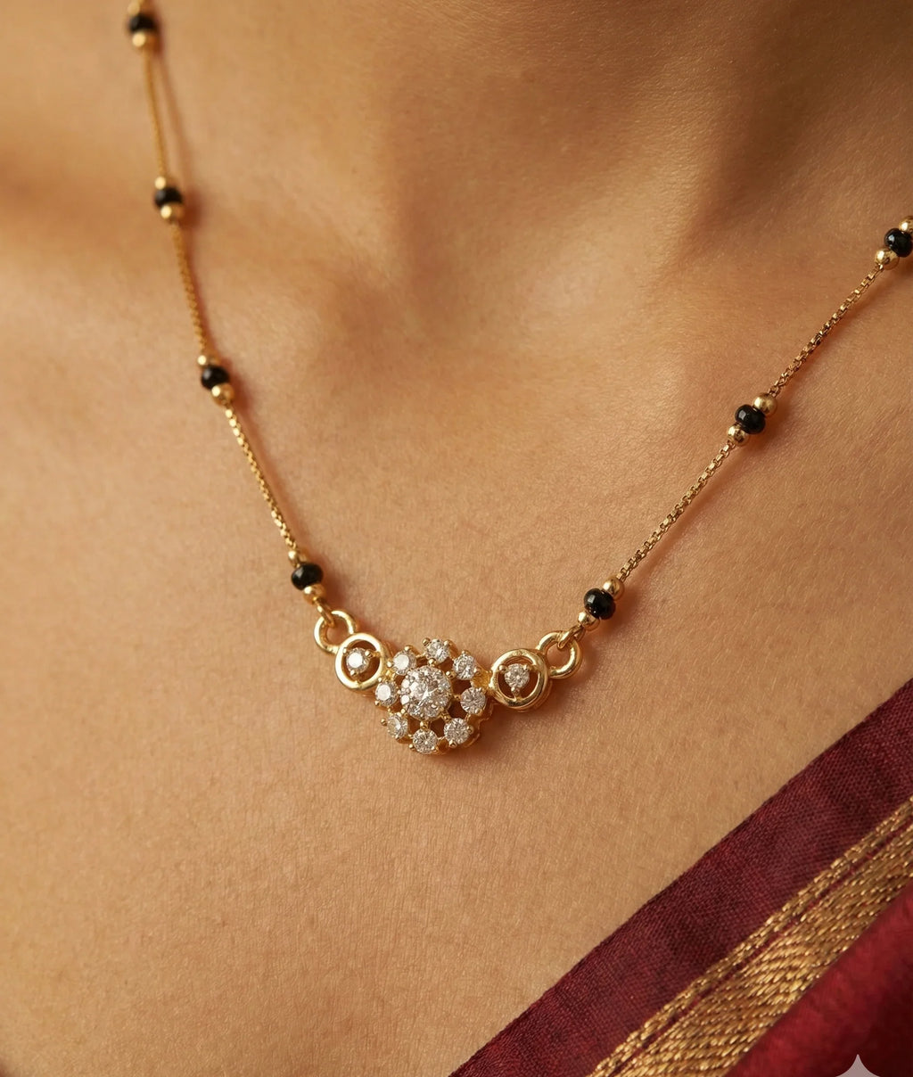 Gold necklace with a diamond pendant on a person wearing a red saree.