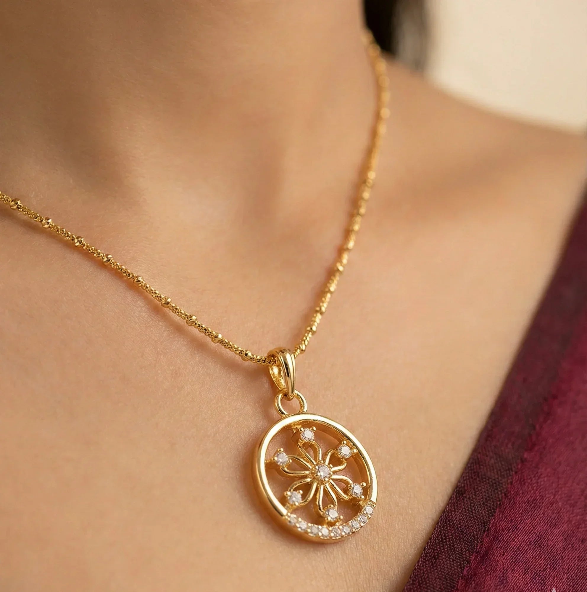 Gold necklace with a decorative pendant worn by a person