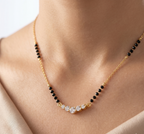 Gold necklace with black and clear beads on a person's neck