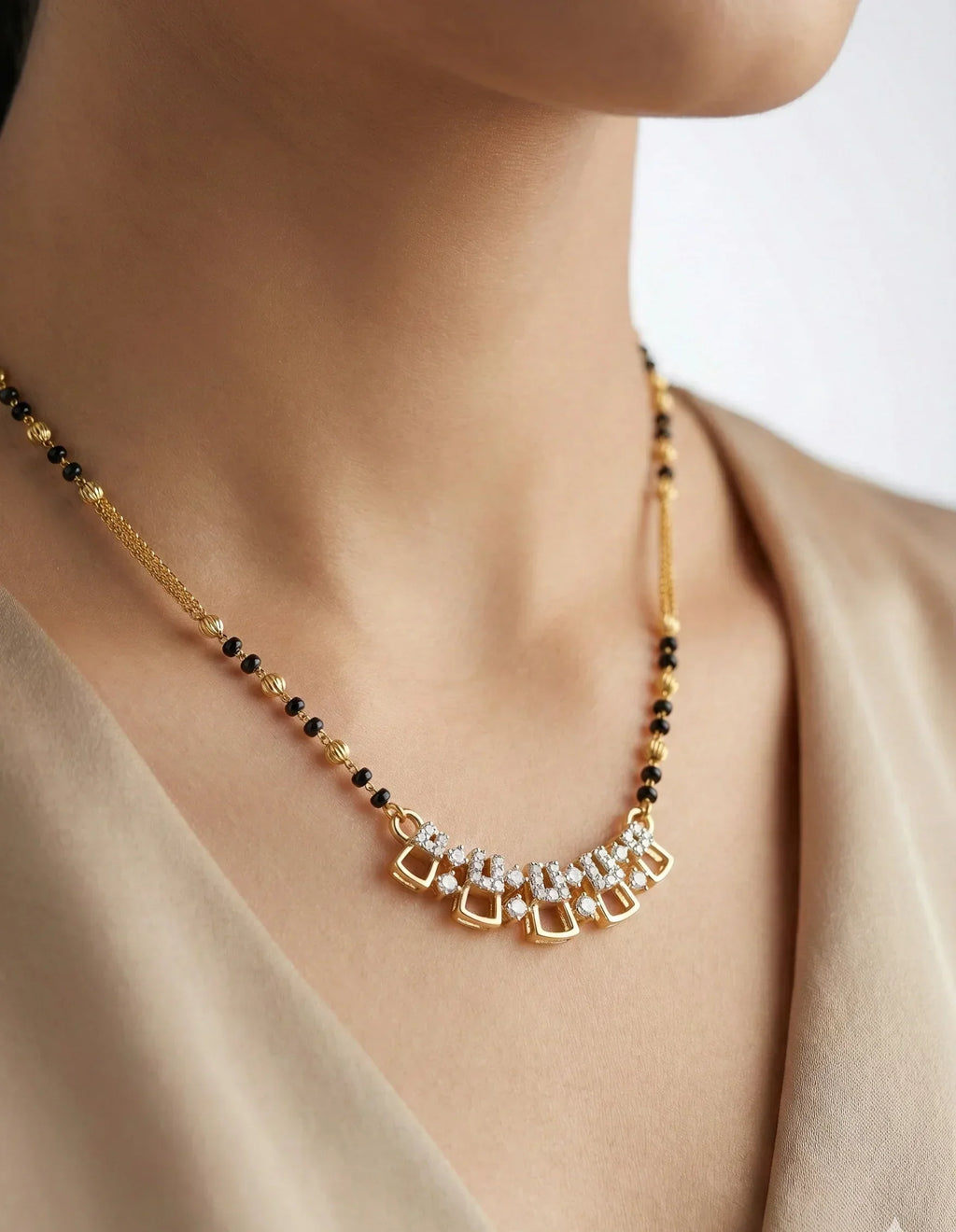 Necklace with gold, black, and clear beads on a person wearing a beige top.