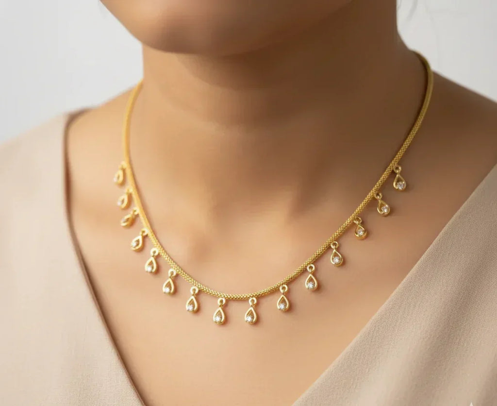 Gold necklace with teardrop pendants on a neutral background