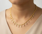 Gold necklace with teardrop pendants on a neutral background
