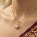 Gold necklace with a star-shaped pendant on a person wearing a maroon saree with gold border.