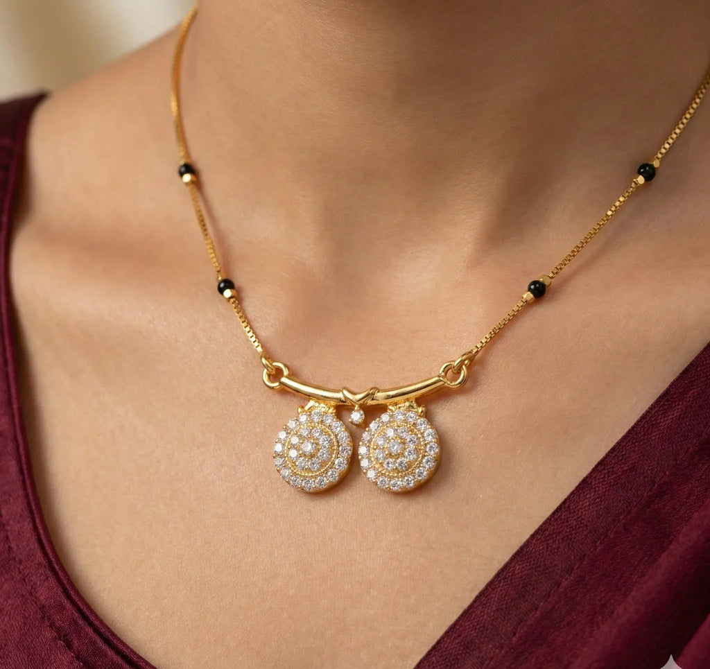 Gold necklace with circular pendants on a person wearing a burgundy top.