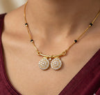 Gold necklace with circular pendants on a person wearing a burgundy top.
