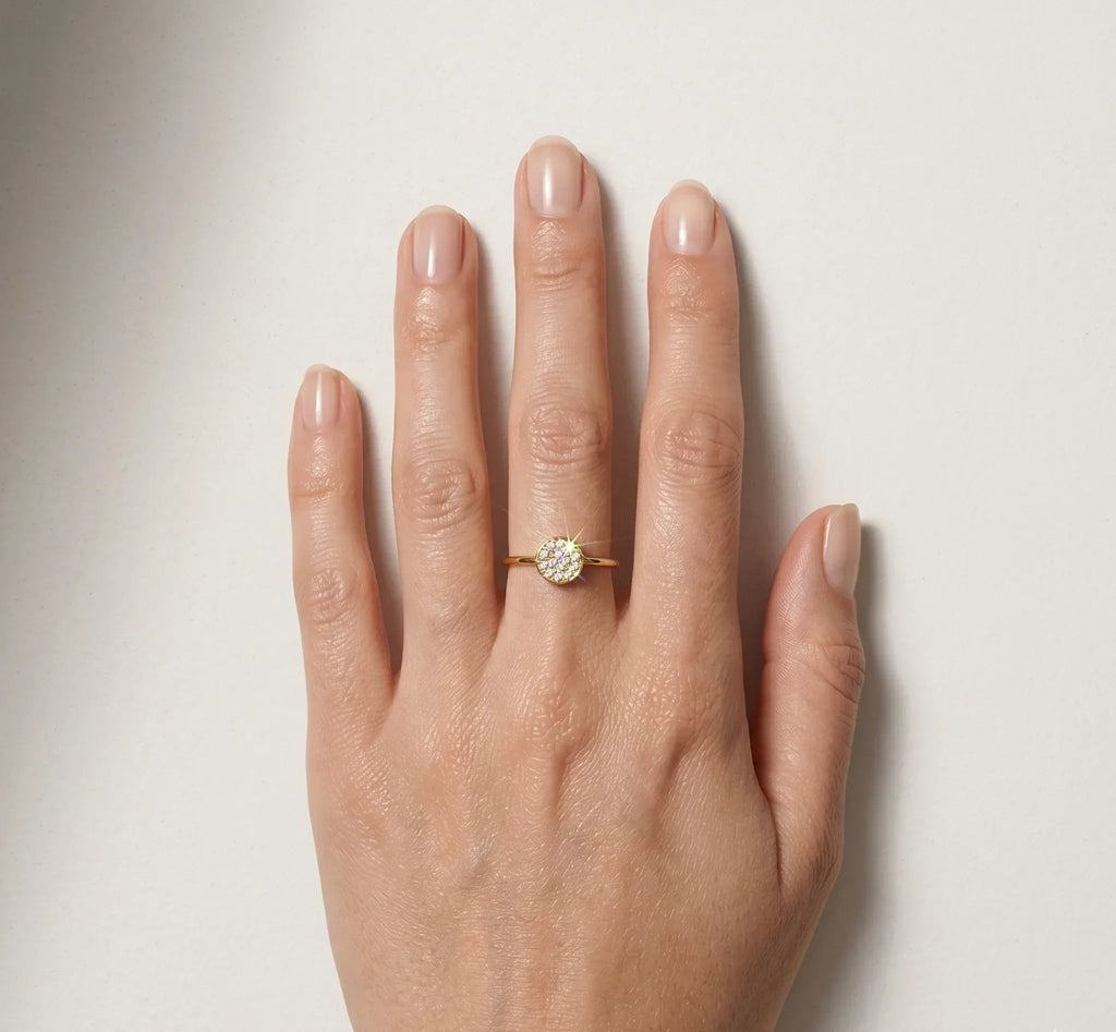 Hand wearing a gold ring with a diamond on a light background