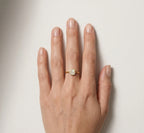 Hand wearing a gold ring with a diamond on a light background