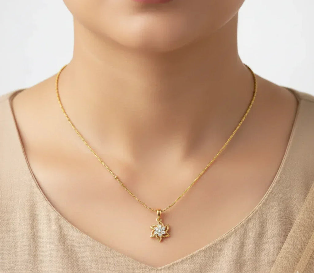 Gold necklace with a star-shaped pendant worn by a person in a beige top.