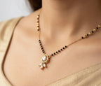 Gold necklace with black beads and a pendant on a person wearing a gold saree.