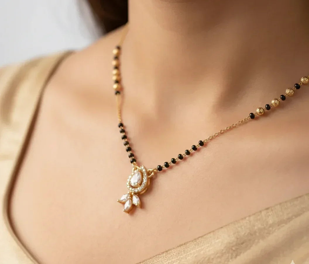 Gold necklace with black beads and a pendant on a person wearing a gold saree.