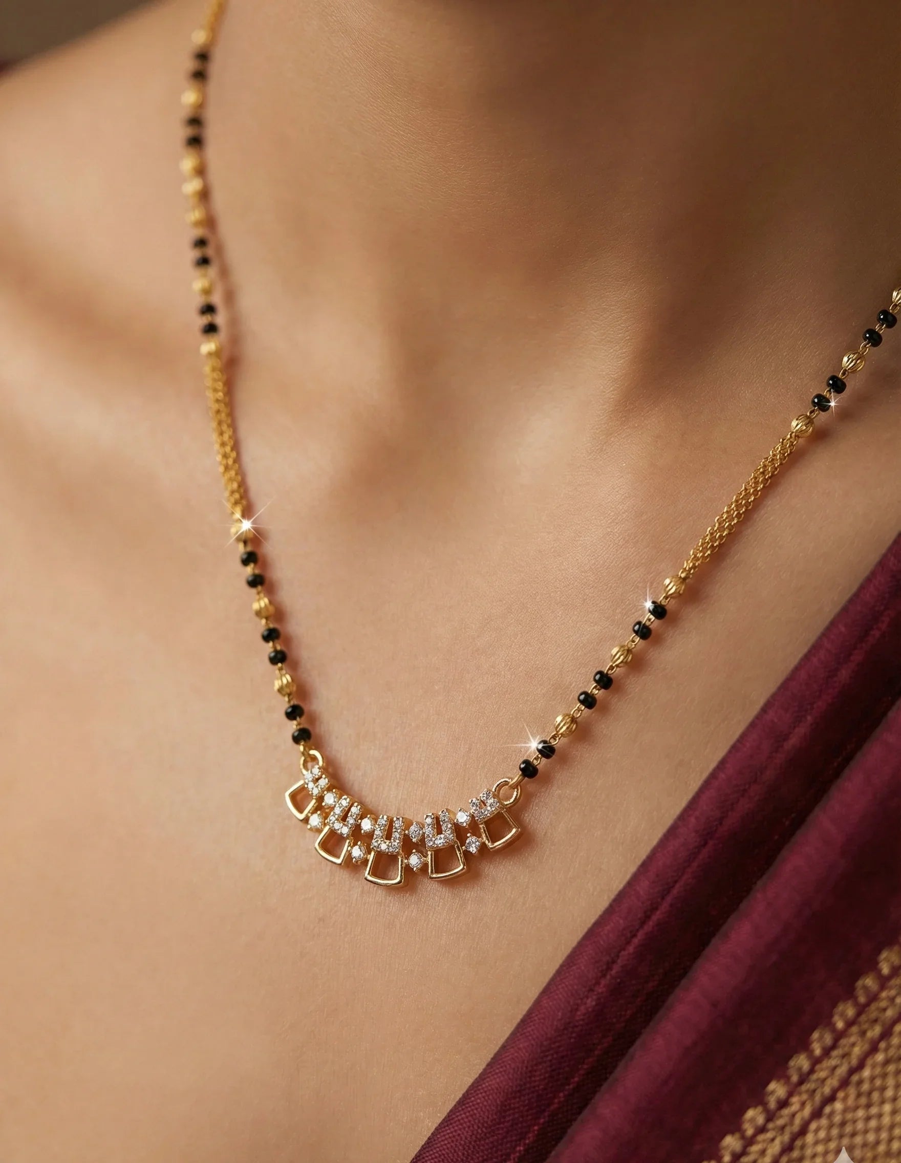 Gold necklace with black beads and pearls on a person wearing a maroon saree.