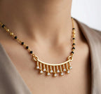 Gold necklace with black beads and small diamonds on a mannequin