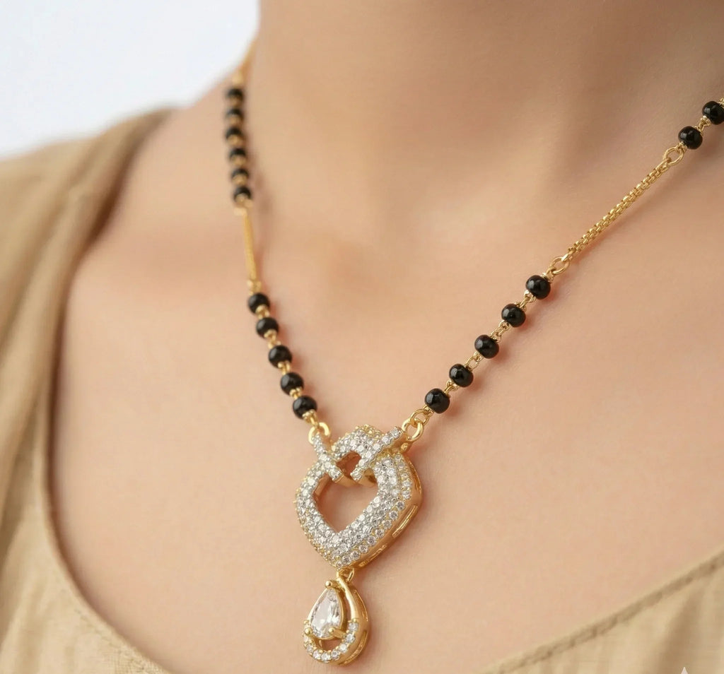 Gold necklace with black beads and a heart-shaped pendant on a mannequin.