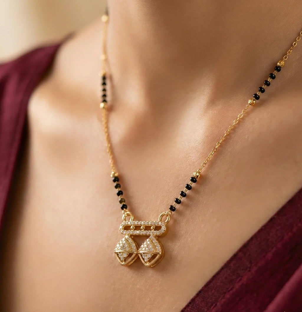 Gold necklace with black beads on a person wearing a burgundy top.