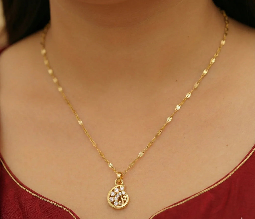 Gold necklace with a pendant on a person wearing a red garment.