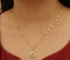 Gold necklace with a pendant on a person wearing a red garment.