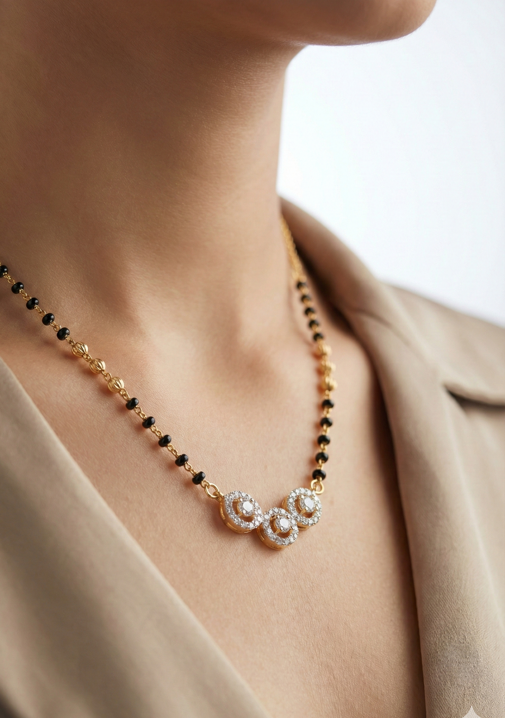 Necklace with black beads and floral pearl design worn by a person in a beige outfit.