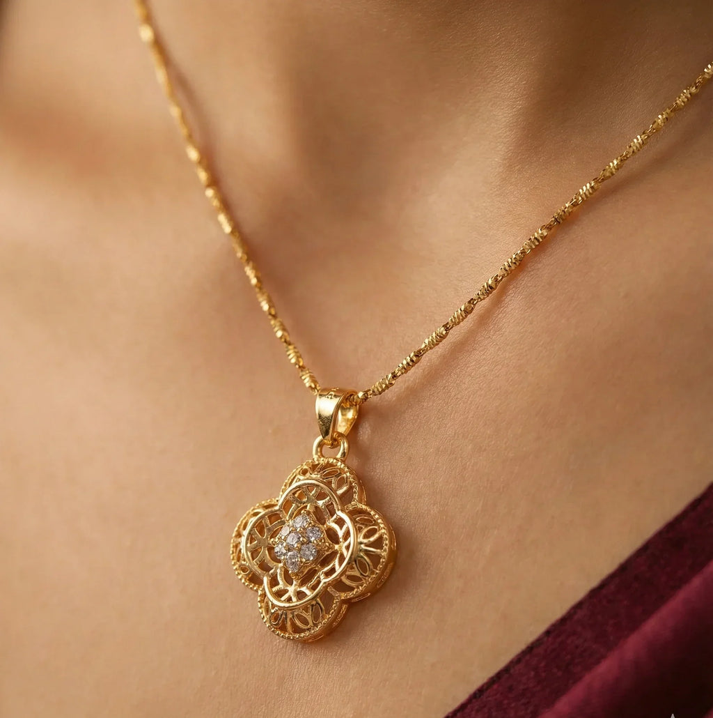 Gold necklace with a diamond pendant on a person wearing a burgundy top.