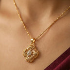 Gold necklace with a diamond pendant on a person wearing a burgundy top.