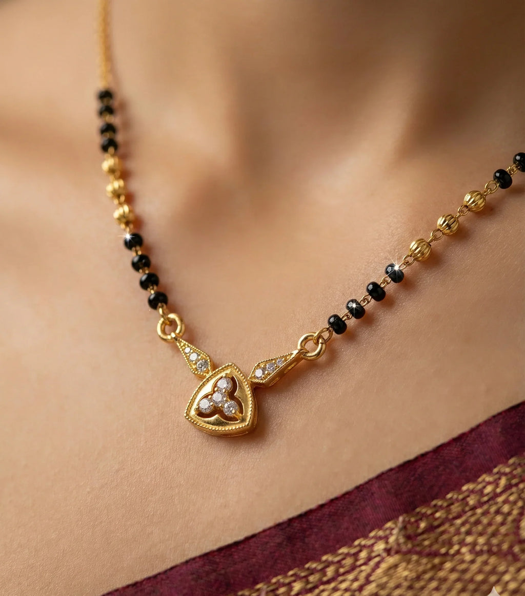 Gold necklace with black beads and a heart-shaped pendant on a blurred background