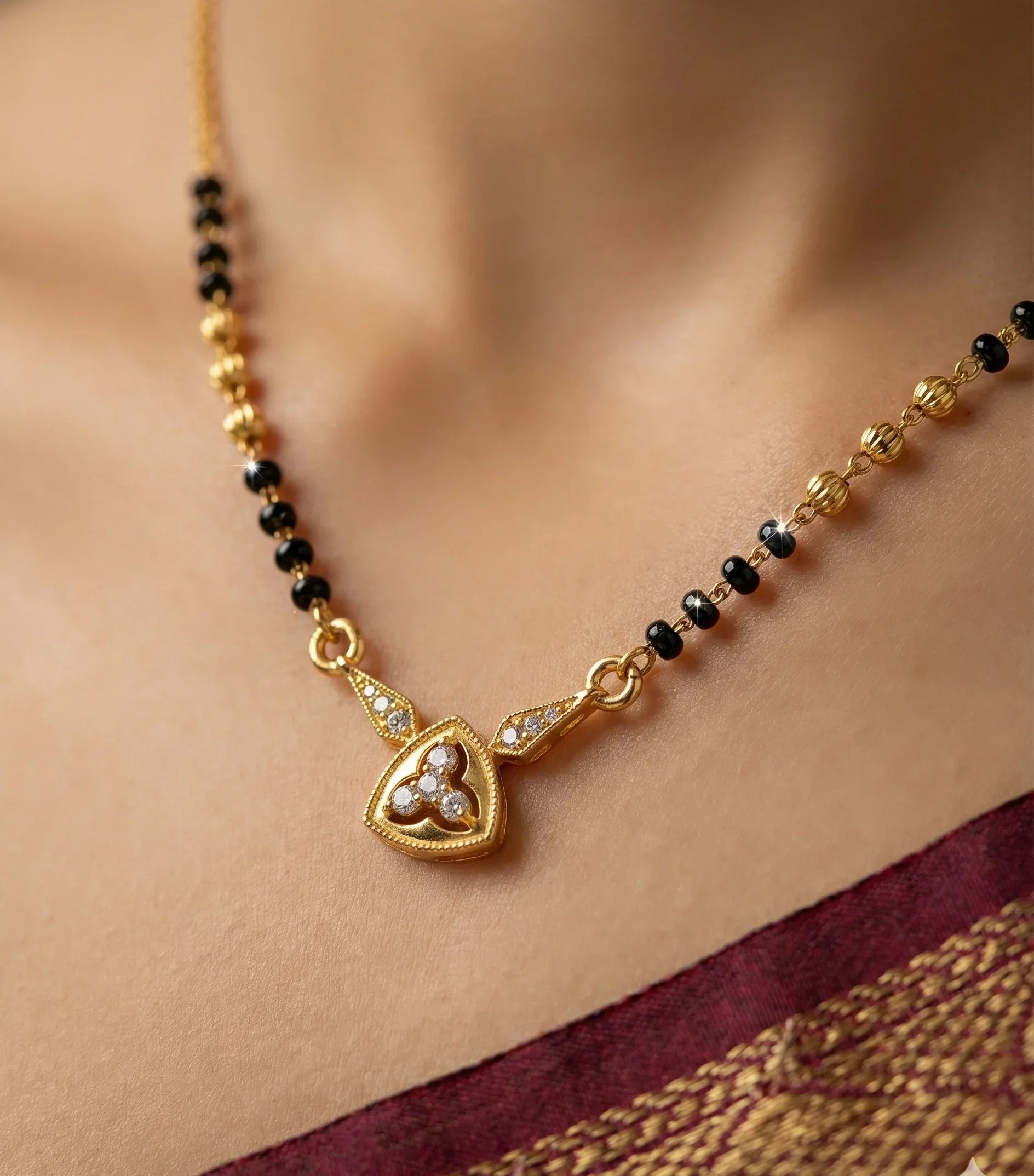 Gold necklace with black beads and a heart-shaped pendant on a blurred background