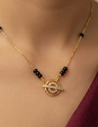 Gold necklace with black beads and a circular pendant on a person's neck.