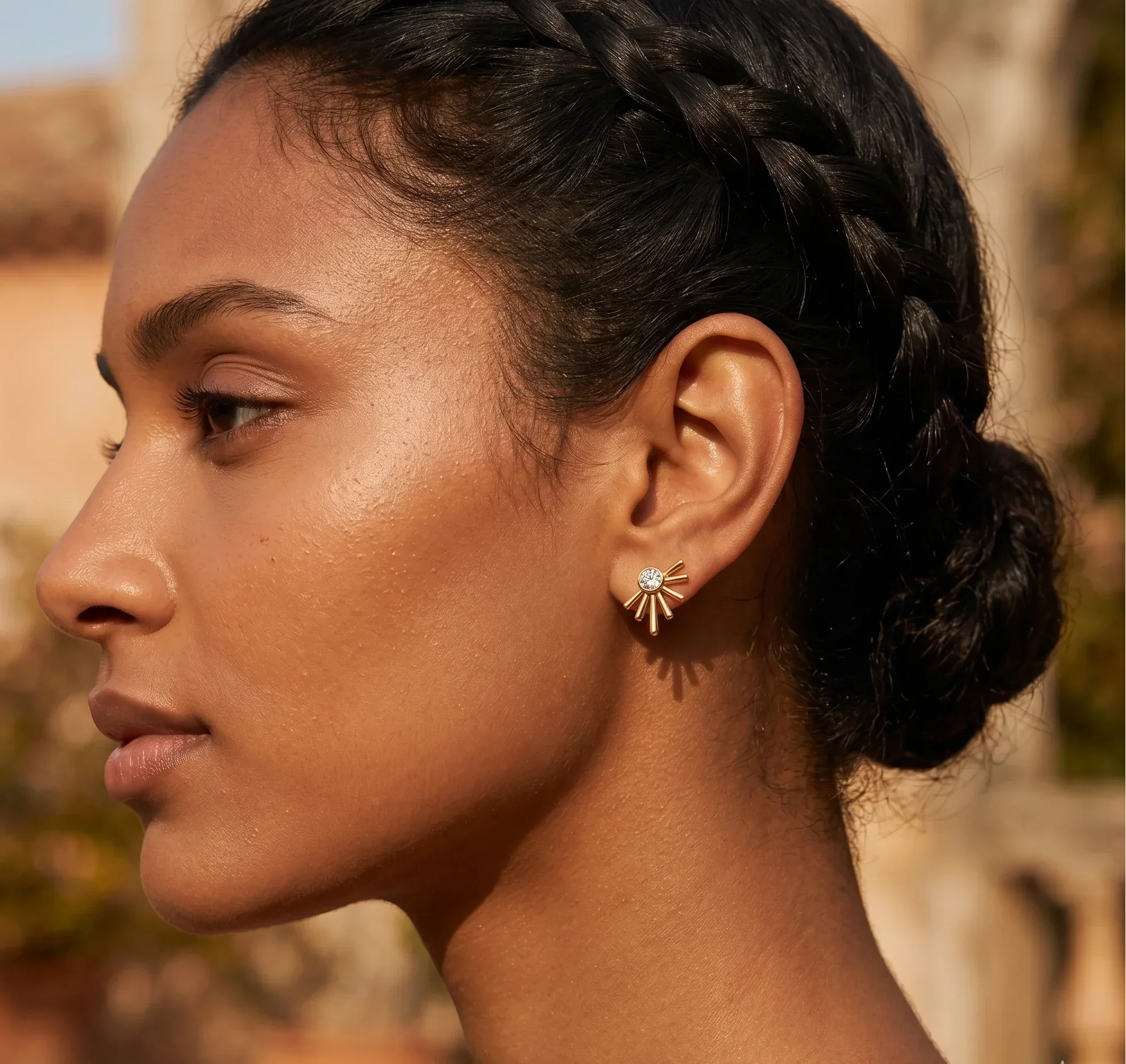 Close-up of a woman's profile with braided hair and a blurred outdoor background