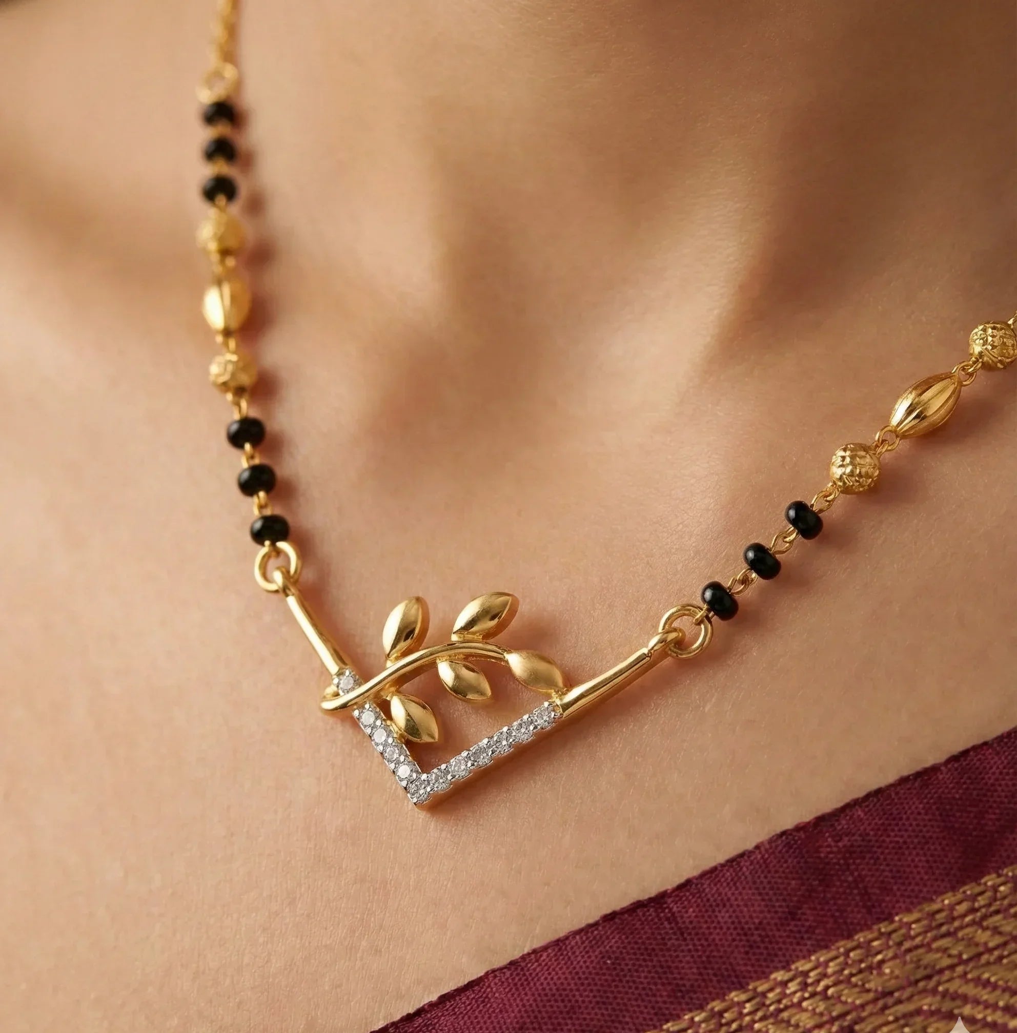 Gold necklace with black beads on a person wearing a saree