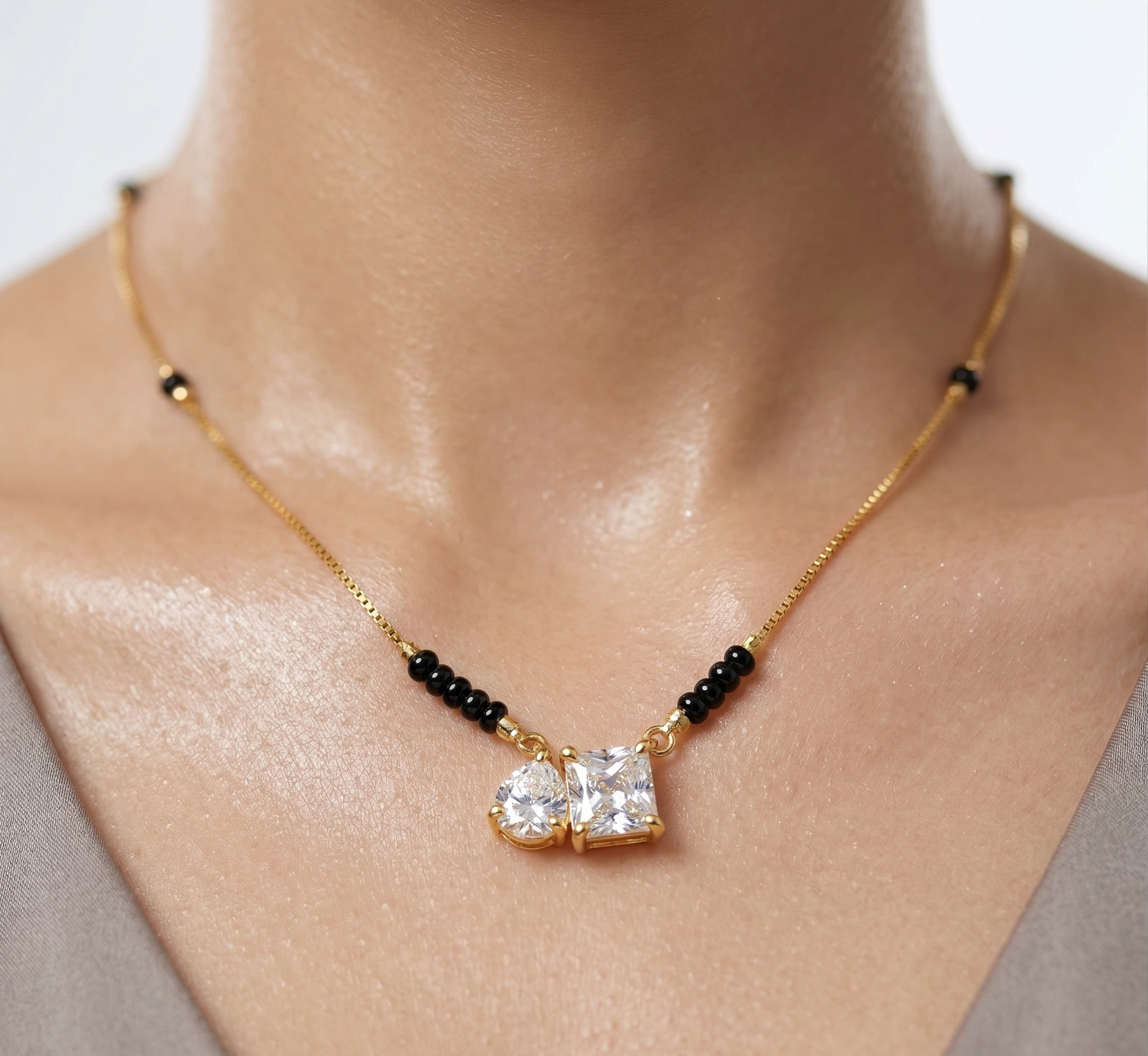 Gold necklace with black beads and two large diamonds on a person's neck.