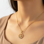 Gold necklace with a decorative pendant on a neutral background