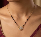 Necklace with black beads and a decorative pendant on a person wearing a red garment.