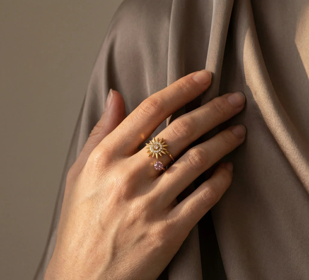 Hand wearing two rings with star-shaped designs on a draped fabric background