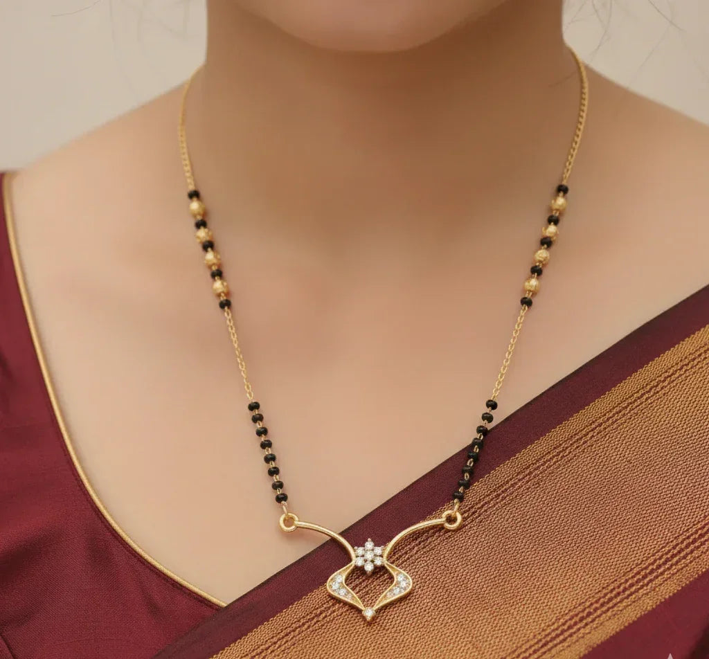 Gold necklace with black beads on a person wearing a maroon saree.