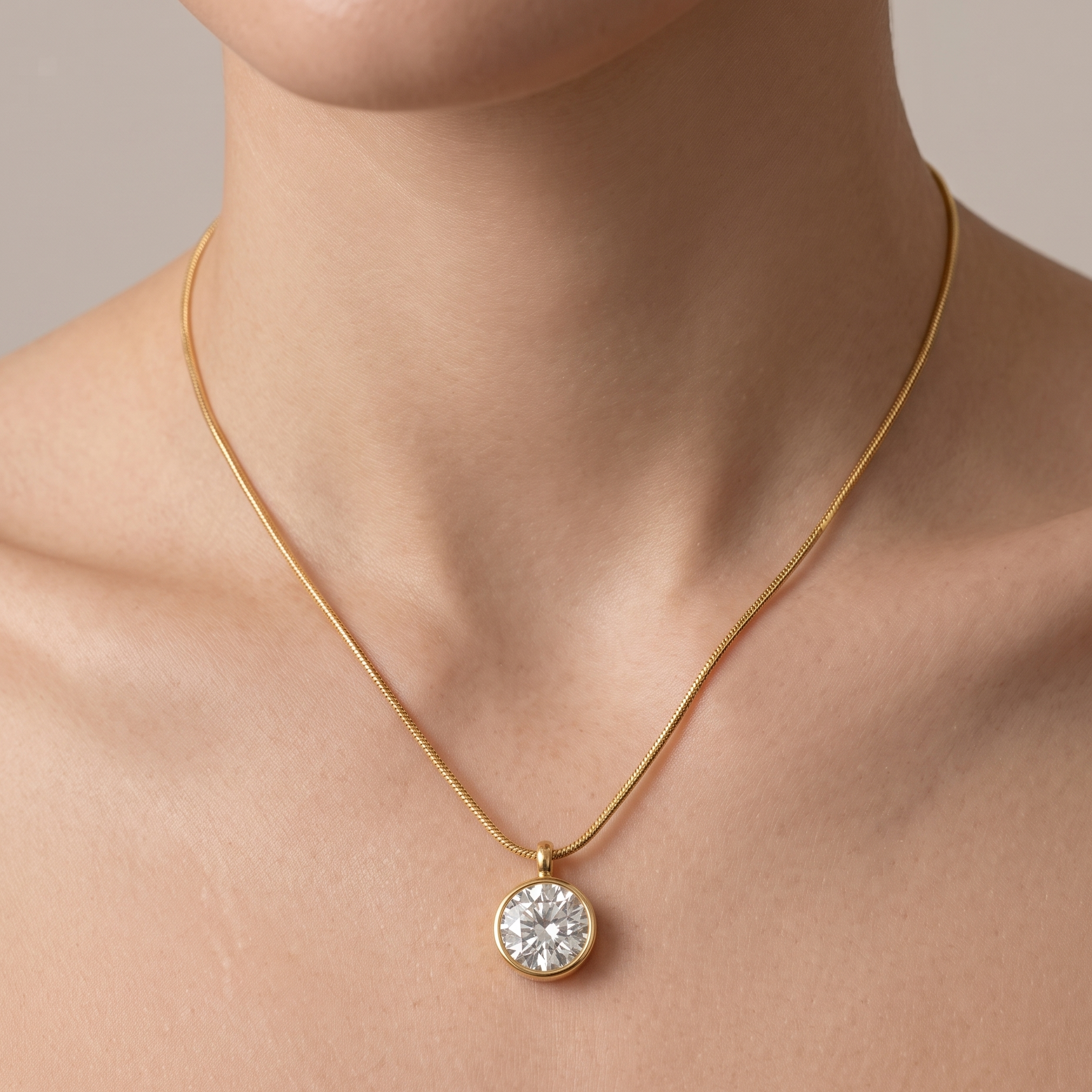 Gold necklace with a diamond pendant on a neutral background