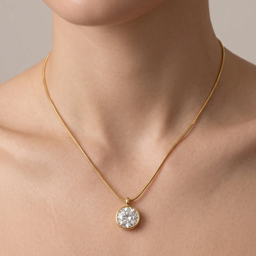 Gold necklace with a diamond pendant on a neutral background