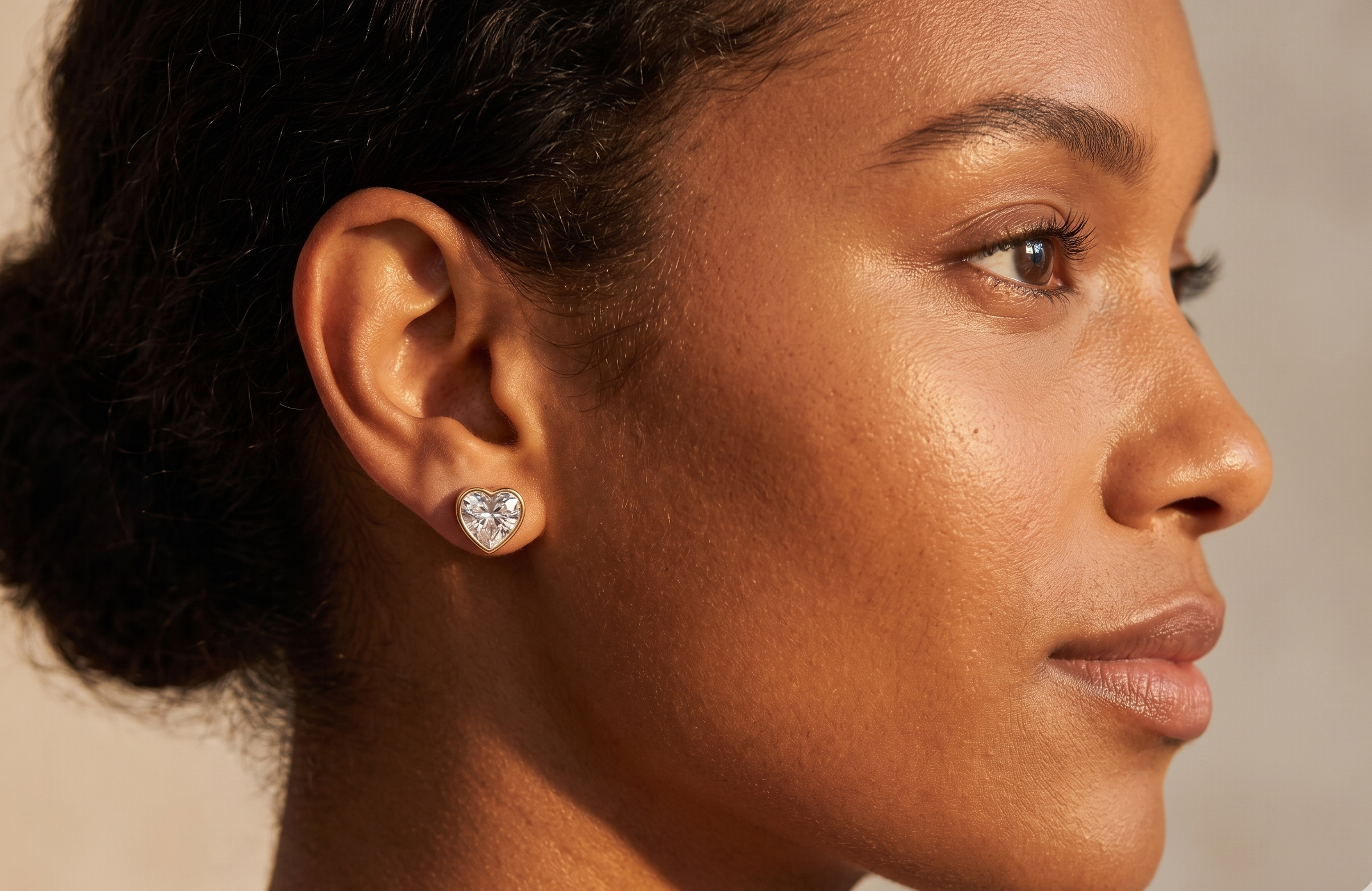 Close-up of a woman wearing a diamond earring with a neutral background