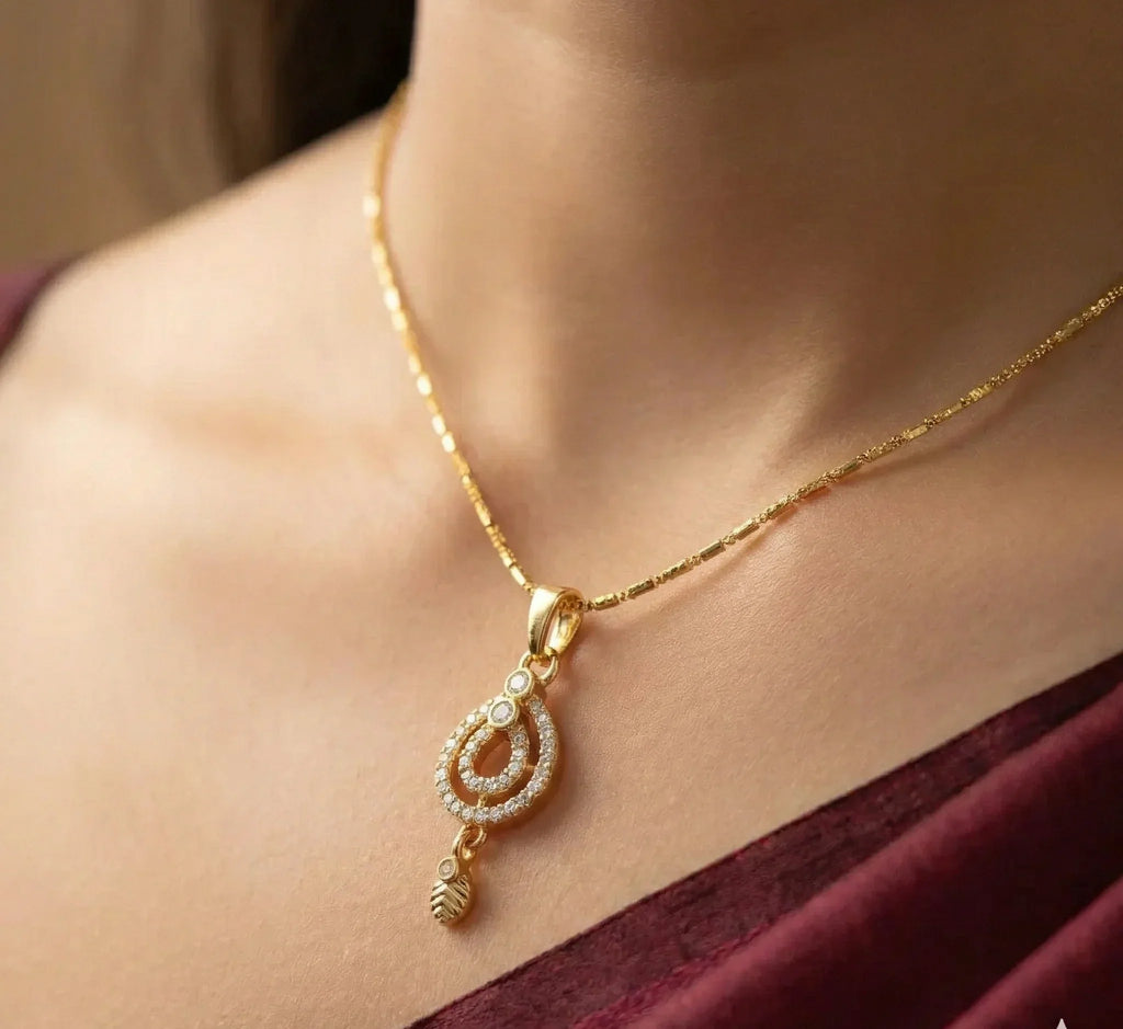 Gold necklace with a pendant worn by a person, against a neutral background