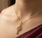 Gold necklace with a pendant worn by a person, against a neutral background