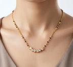 Necklace with black and gold beads on a model against a neutral background