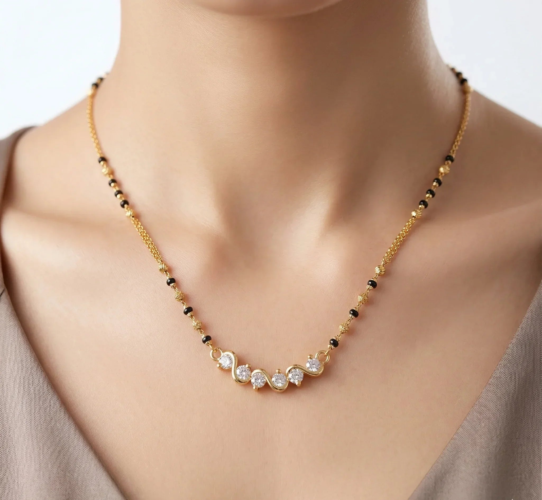 Necklace with black and gold beads on a model against a neutral background