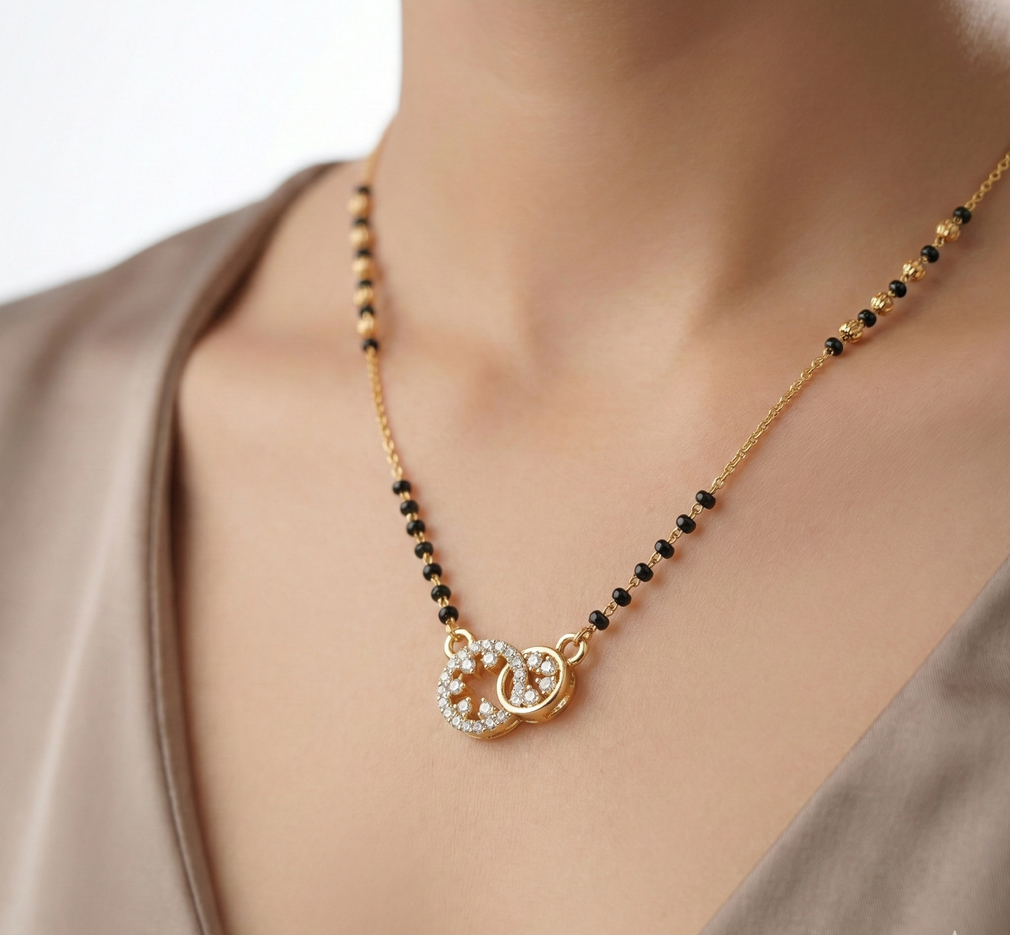 Gold necklace with black beads and a heart pendant on a model