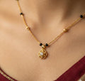 Gold necklace with a pendant on a person wearing a red garment