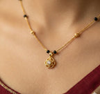 Gold necklace with a pendant on a person wearing a red garment