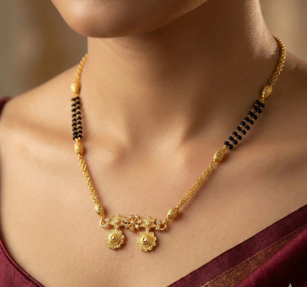 Gold necklace with black beads on a person wearing a maroon saree.