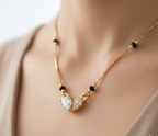 Gold necklace with a heart-shaped pendant on a neutral background