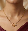 Gold necklace with a circular pendant on a person wearing a maroon top.