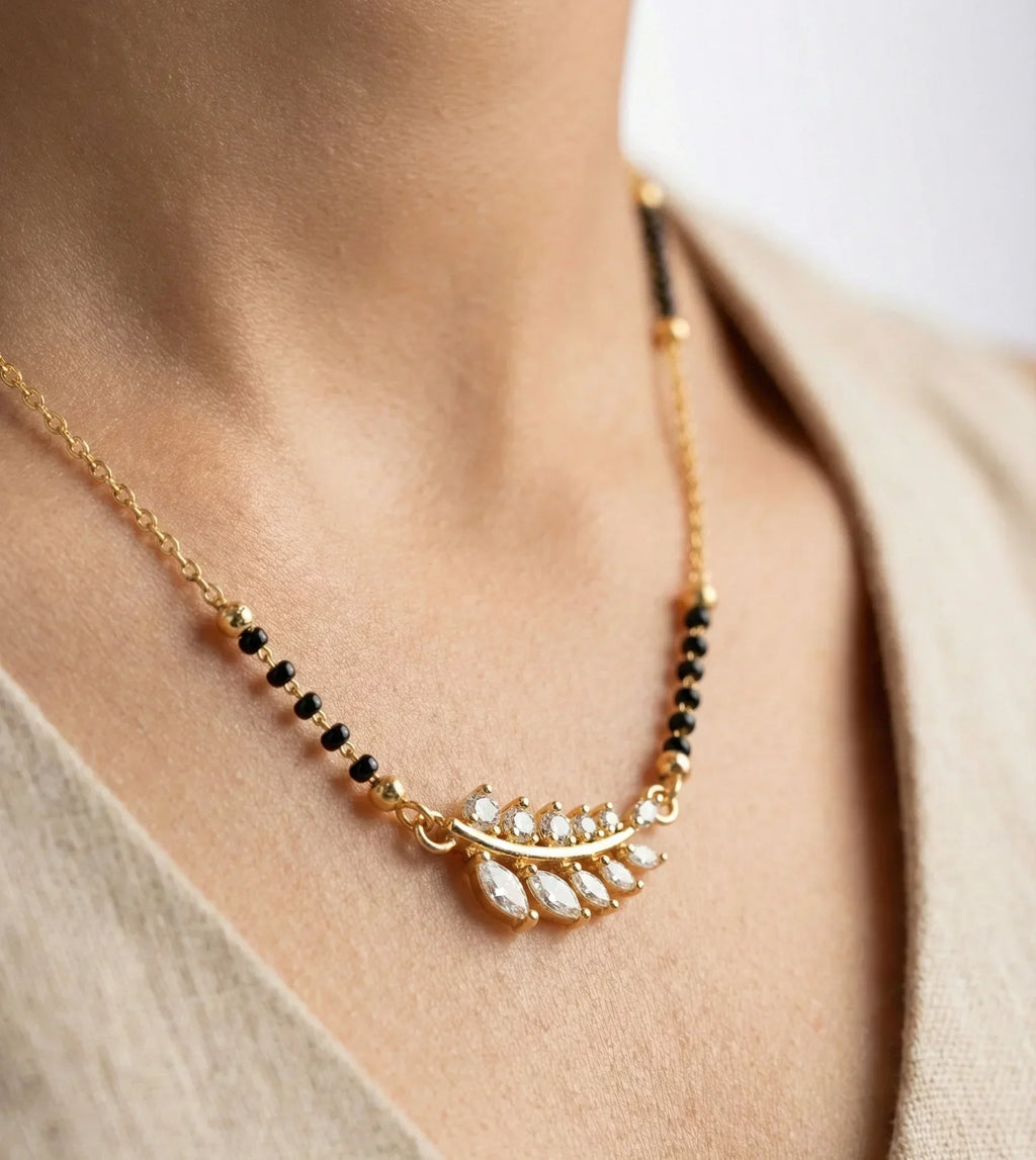 Gold necklace with black beads and white stones worn by a person